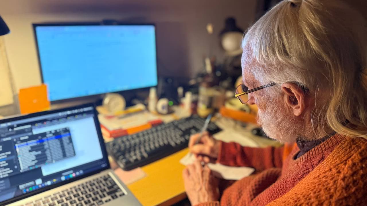 An older client receiving calm digital support from Arvora at a desk with a laptop and monitor